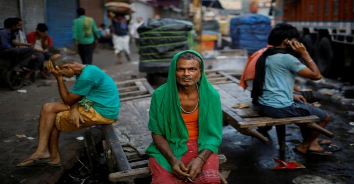 FILE PHOTO: Migrant labourers sit on a handcart as they wait for work at a wholesale market in