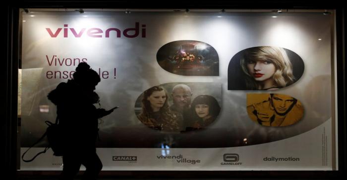 A woman walks pass by a sign of Vivendi at the main entrance of the entertainment-to-telecoms