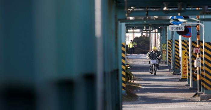 FILE PHOTO: A worker cycles near a factory at the Keihin industrial zone in Kawasaki