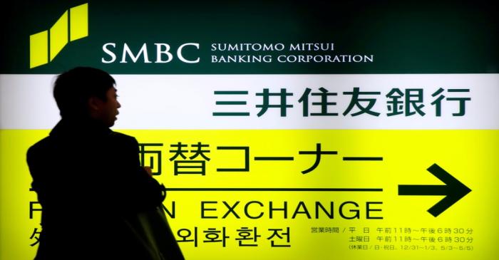 FILE PHOTO: A man walks past a sign board of Sumitomo Mitsui Banking Corporation, part of SMFG