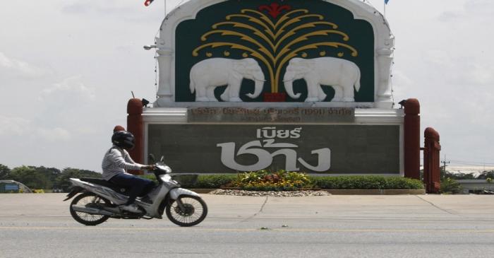 A man rides his motorcycle past a beer factory belonging to Thai Beverage in Ayutthaya province