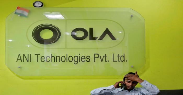 An employee speaks over his phone as he sits at the front desk inside the office of Ola cab