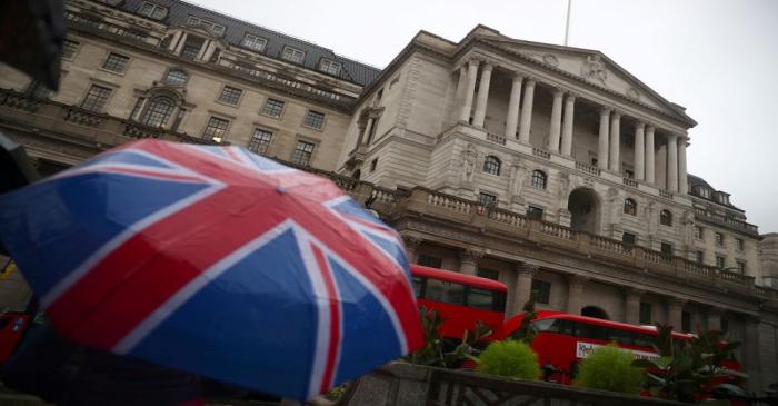 FILE PHOTO: A pedestrian shelters under an umbrella in front of the Bank of England, in London