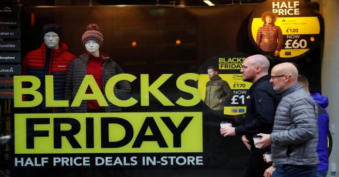 People walk past a sign advertising Black Friday offers in the window of a Blacks outdoor
