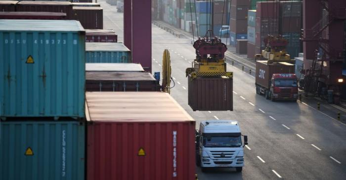 Trucks transport shipping containers at Qianwan container terminal of Qingdao port in Qingdao