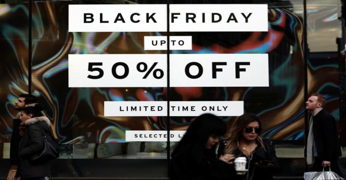 Pedestrians walk past a sign in a store window on Oxford Street on 'Black Friday' in London