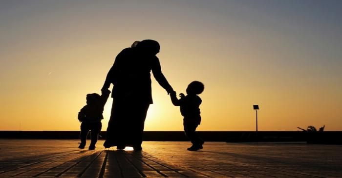 FILE PHOTO: A woman walks with her two children at sunset near the seashore in Benghazi