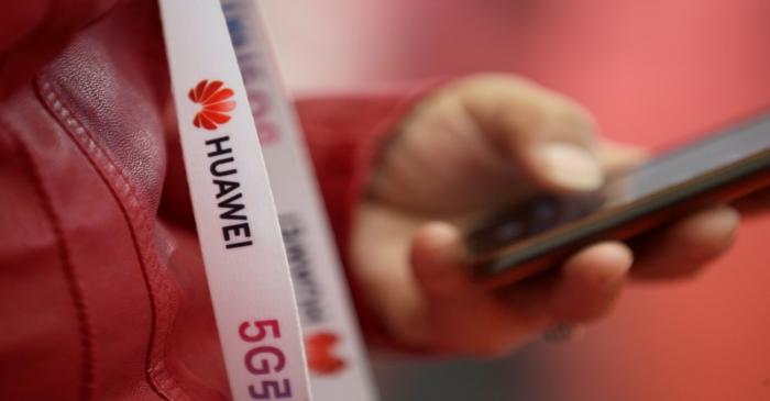 An attendee wears a badge strip with the logo of Huawei and a sign for 5G at the World 5G