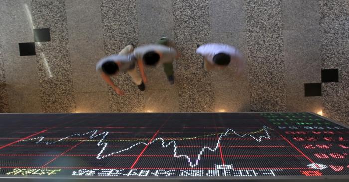 People walk under an electronic board showing stock information at the Shanghai Stock Exchange