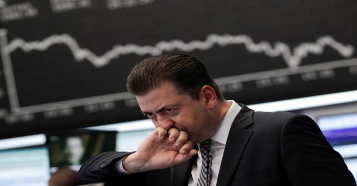 FILE PHOTO: Trader reacts at his desk in front of the DAX board at the Frankfurt stock exchange