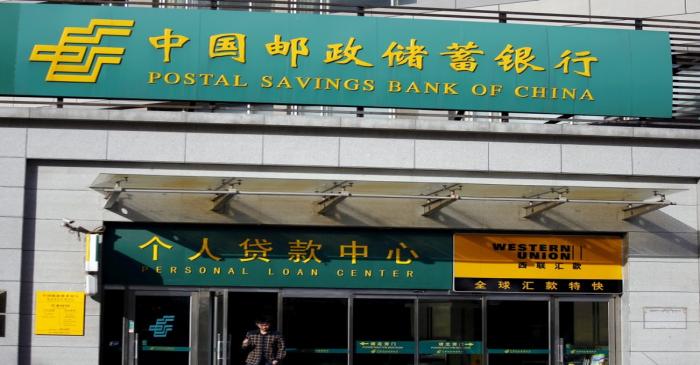 FILE PHOTO: Man walks out of a Postal Savings Bank of China branch in Beijing