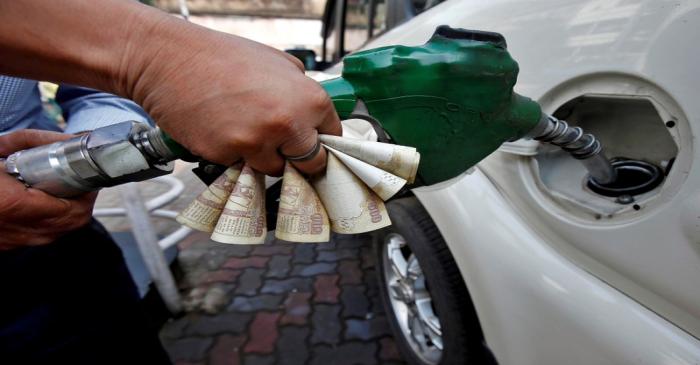 FILE PHOTO: A worker fills diesel in a car as he holds 500 Indian rupee banknotes at a fuel