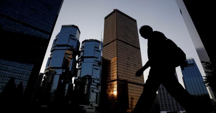 A man walks past buildings at a business district in Hong Kong