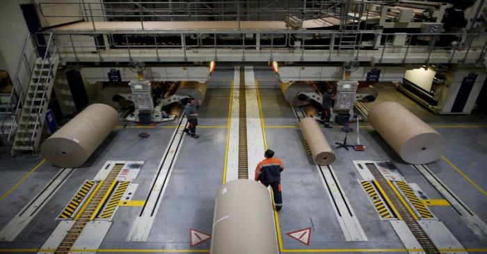 Employees work on giant reels of paper at the carboard box manufacturing company DS Smith