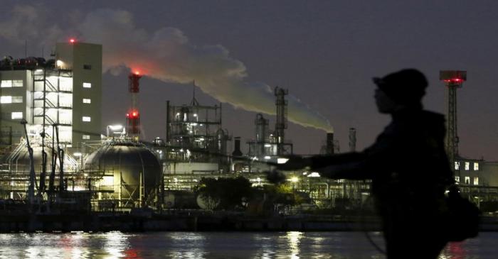 Smoke is emitted from a chimney as a man fishes at the Keihin industrial zone in Kawasaki