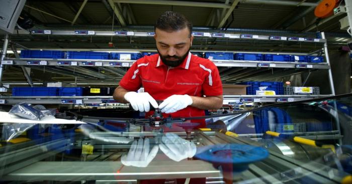 FILE PHOTO: An employee of German car manufacturer Porsche works on a windshield of a sports