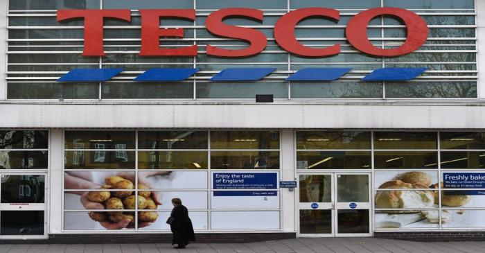 Woman walks past a Tesco supermarket in central London