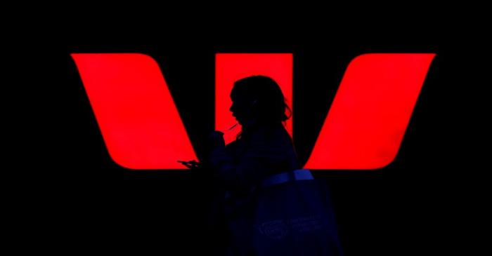FILE PHOTO: A woman walks past an illuminated logo for Australia's Westpac Bank in Sydney