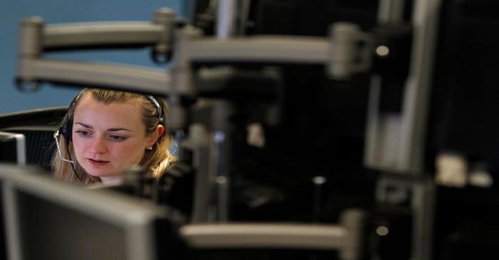 A trader monitors her screen on a trading floor in London