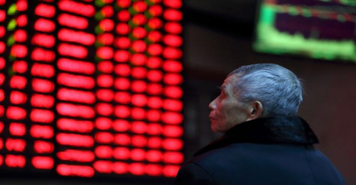 FILE PHOTO:  A man looks on in front of an electronic board showing stock information at a