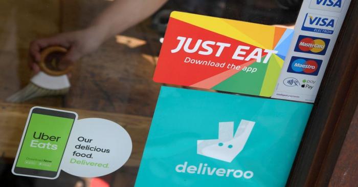 FILE PHOTO: Signage for Just Eat is seen next to Uber Eats and Deliveroo advertisements on the