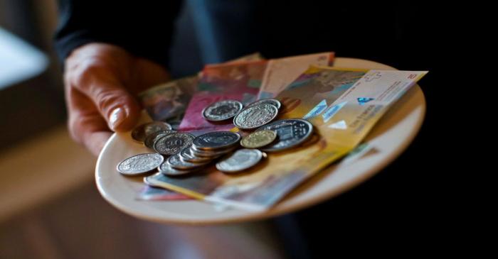 A waitress presents a plate with various Swiss Franc coins and notes in this picture