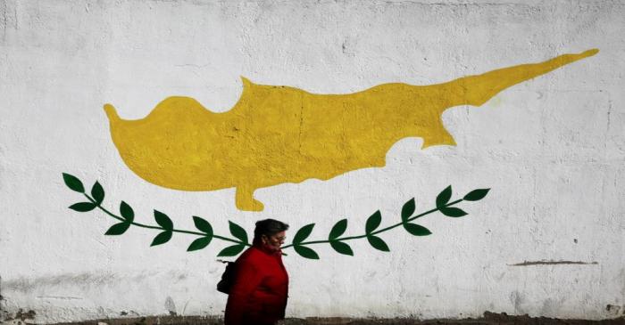 A woman walks in front of Cypriot flag painted on a wall in capital Nicosia