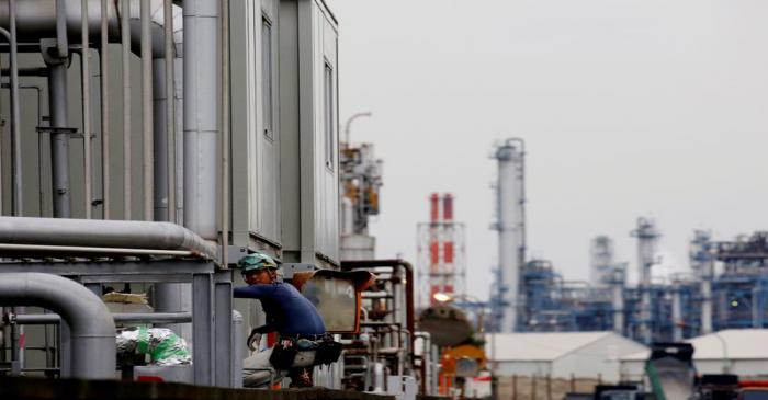 FILE PHOTO:A worker is seen in front of facilities and chimneys of factories at the Keihin