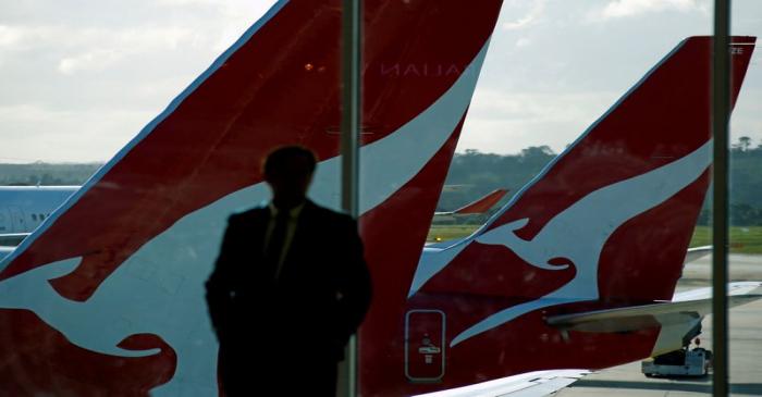 FILE PHOTO: A passenger stands in front of a window where Qantas planes are parked at Melbourne