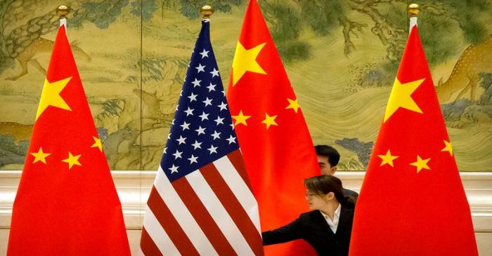 FILE PHOTO: Chinese staff members adjust U.S. and Chinese flags before the opening session of