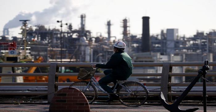 FILE PHOTO: A worker cycles near a factory at the Keihin industrial zone in Kawasaki