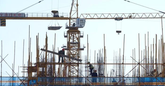 Vanke sign is seen above workers working at the construction site of a residential building in