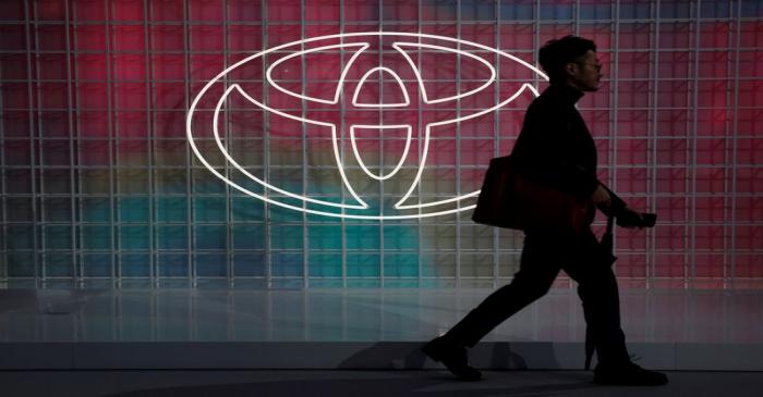 A man walks past a Toyota logo at the Tokyo Motor Show