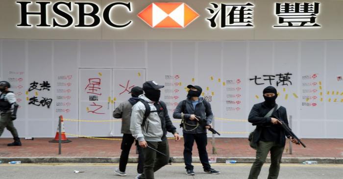 Armed undercover police officers guard a vandalized HSBC bank branch in Wan Chai during