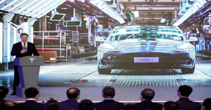 Tesla Inc CEO Elon Musk speaks next to a screen showing an image of Tesla Model 3 car during an
