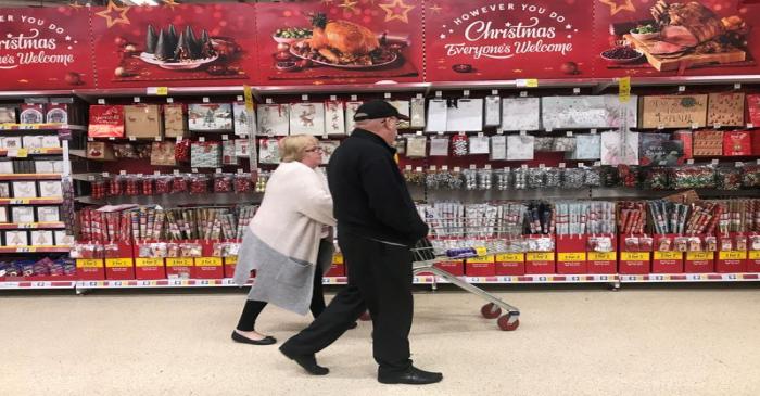FILE PHOTO: A woman pushes a shopping trolley past Christmas decorations for sale in a Tesco