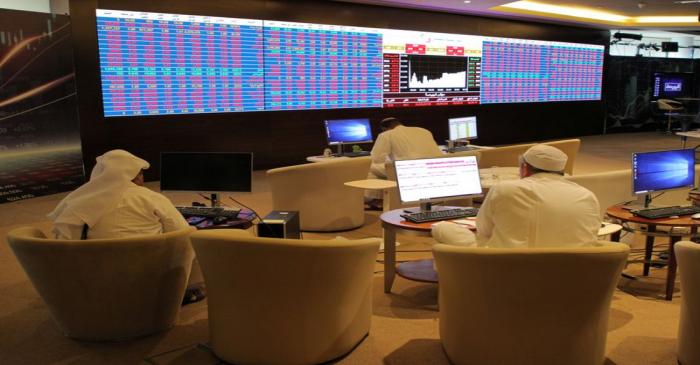 Qatar's traders look at share prices on an electronic display at the Doha Stock Exchange in