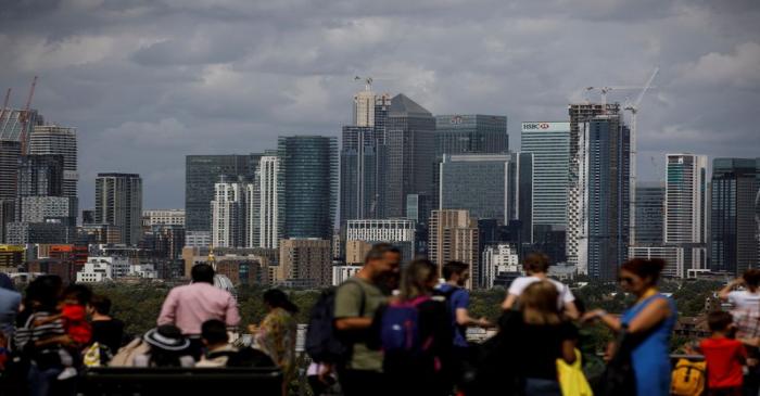 People look out onto the Canary Wharf financial district as they stand at a viewing area in