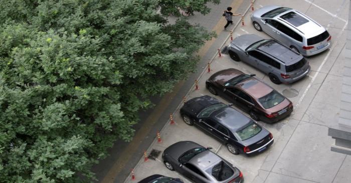 A woman walks past cars in Beijing