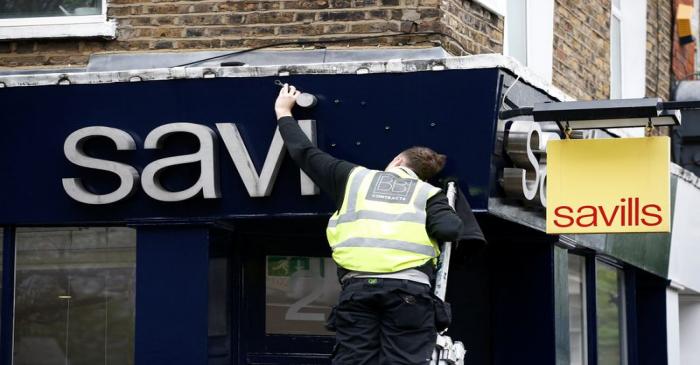 A worker puts up at Savills estate agents sign in London