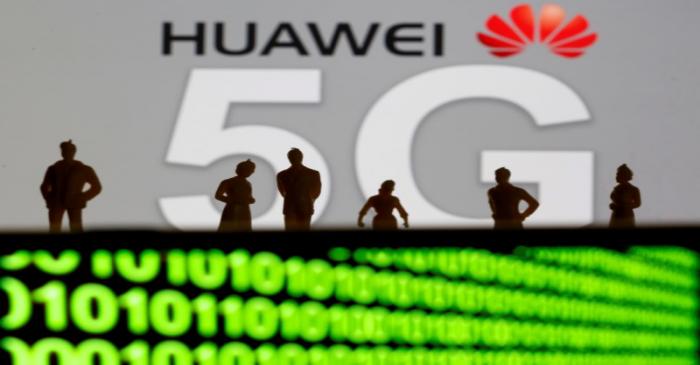 FILE PHOTO: Small toy figures are seen in front of a displayed Huawei and 5G network logo in