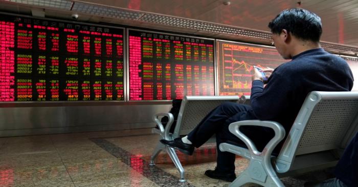 FILE PHOTO:  An investor uses his mobile phone in front of a stock quotation board at a