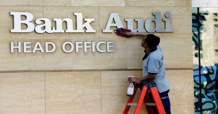 FILE PHOTO: A worker cleans the logo of Bank Audi in Beirut