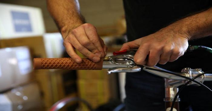 Gabe Ortiz fastens grips to the handlebars of one of the company's products