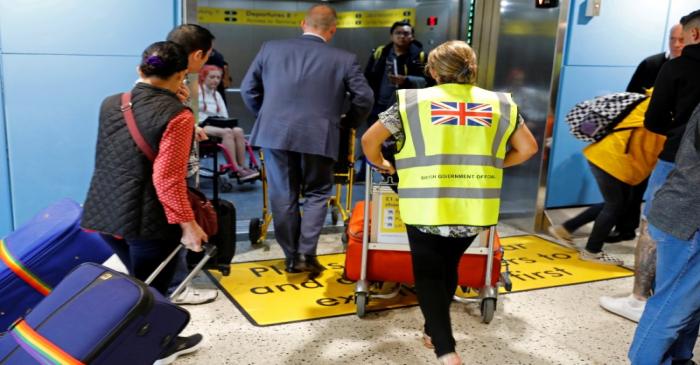 FILE PHOTO: An official assists passengers at Manchester Airport, Britain