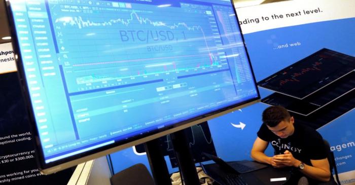 FILE PHOTO: A man works beneath a display showing the market price of Bitcoin on the floor of