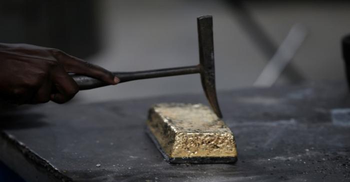 An employee uses a hammer to clean a gold ingot during the refining process at AGR (African