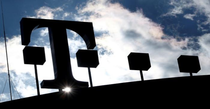 FILE PHOTO: The logo of Deutsche Telekom AG is silhouetted against the sun and clouds atop of