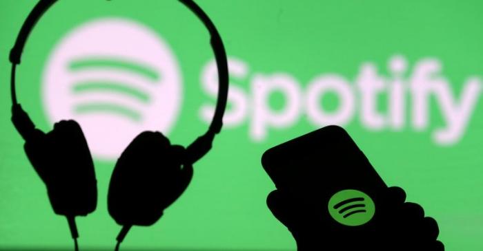 FILE PHOTO: A smartphone and a headset are seen in front of a screen projection of Spotify