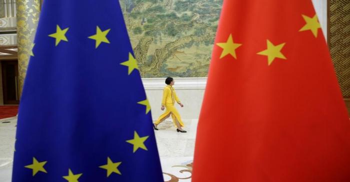 An attendant walks past EU and China flags ahead of the EU-China High-level Economic Dialogue